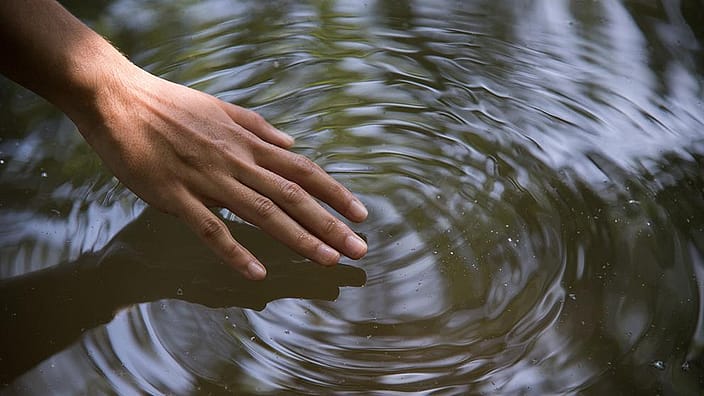 рука трогает воду